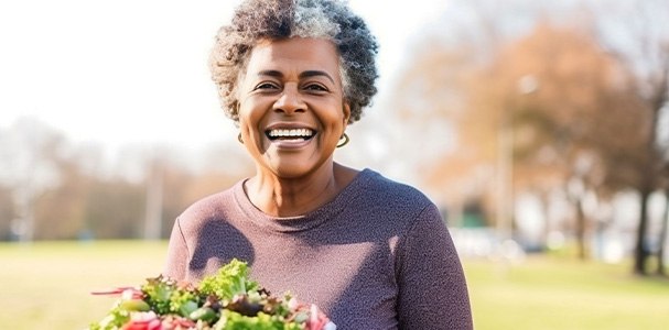 Smiling woman holding plate with salad outside