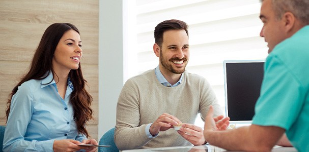 Dentist and couple talking in dental office