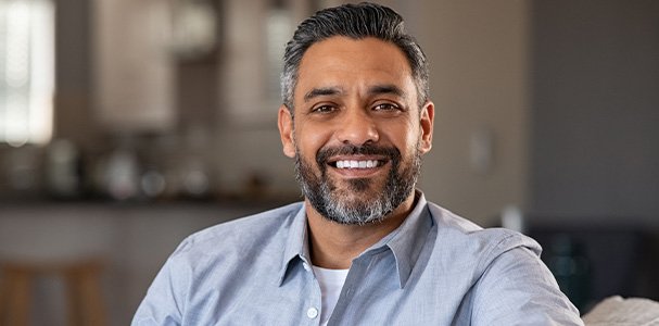 Man in blue button-up smiling at home