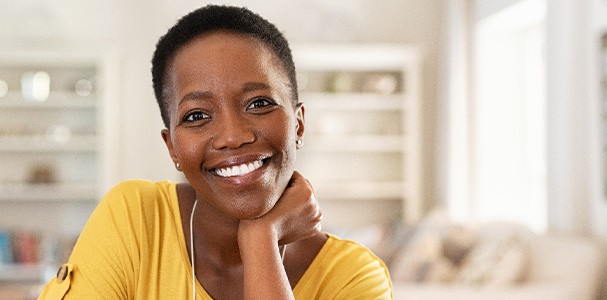 Woman in yellow shirt smiling at home