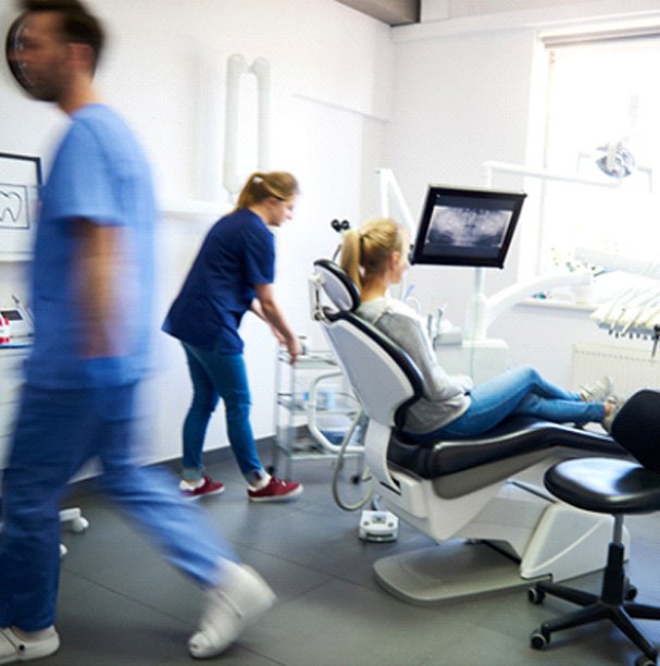 A blurred view of dentists and a woman in a dental clinic