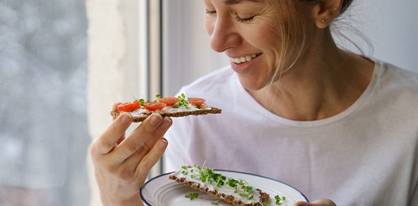 Woman smiling while eating healthy snack at home