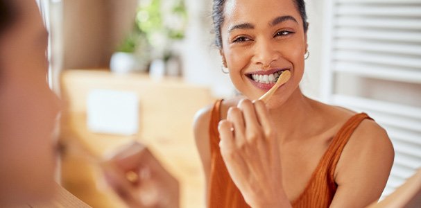 Woman smiling while brushing her teeth