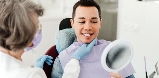 Man smiling at reflection in mirror with dentist