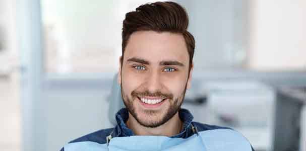 Man in blue shirt smiling in dental chair